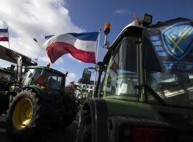 The Farmers Defense Force flag, right, and Dutch flags, fly in the wind on an intersection blocked by tractors in The Hague, Netherlands, Wednesday, Feb. 19, 2020. AP