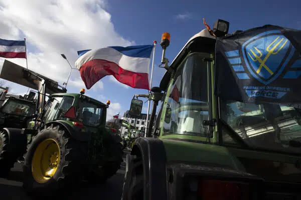 The Farmers Defense Force flag, right, and Dutch flags, fly in the wind on an intersection blocked by tractors in The Hague, Netherlands, Wednesday, Feb. 19, 2020. AP
