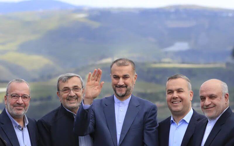 Iranian Foreign Minister Hossein Amirabdollahian, center, waves as he stands with Hezbollah members and lawmakers as the Israeli side seen in the background, during his visit to Iran park, in the village of Maroun el-Rass on the Lebanon-Israel border, south Lebanon, Friday, April 28, 2023. AP