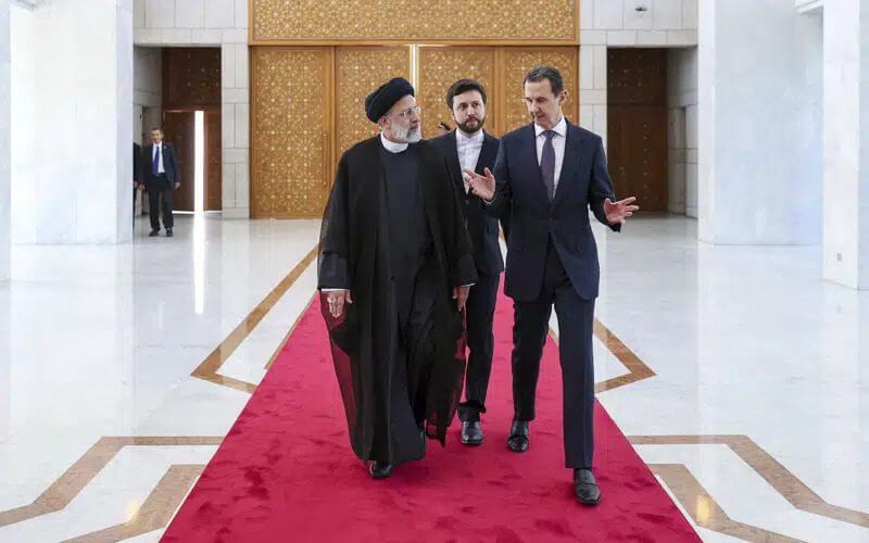 In this photo released by the office of the Iranian Presidency, President Ebrahim Raisi, left, listens to his Syrian counterpart Bashar Assad during a welcoming ceremony in Damascus, Syria, Wednesday, May 3, 2023. (Iranian Presidency Office via AP)