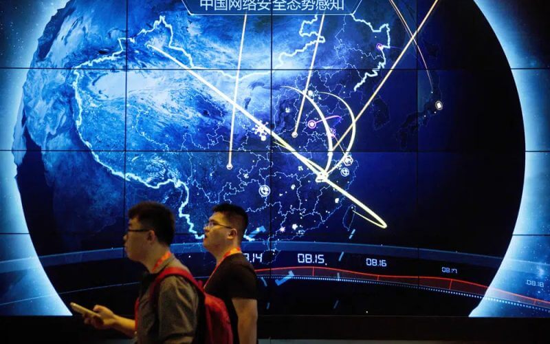 Attendees walk past an electronic display showing recent cyberattacks in China at the China Internet Security Conference in Beijing, on Sept. 12, 2017. (AP Photo/Mark Schiefelbein, File)