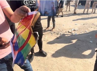 A protester burns a LGBTQ+ rainbow flag as hundreds of followers of the influential Iraqi Shiite cleric and political leader Muqtada Sadr stand outside the Swedish embassy in Baghdad, Iraq, Thursday, June 29, 2023, in protest of the burning of a Quran in Sweden. (AP Photo/Ali Jabar)
