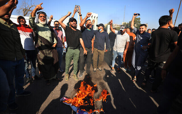 Supporters of Shiite Muslim leader Moqtada Sadr burn a rainbow flag outside the Swedish embassy in Baghdad, after they breached the building over the burning of the Quran by an Iraqi living in Sweden, on June 29, 2023. (Ahmad Al-Rubaye/AFP)