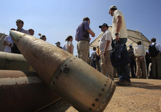 Activists and international delegations stand next to cluster bomb units, during a visit to a Lebanese military base at the opening of the Second Meeting of States Parties to the Convention on Cluster Munitions, in the southern town of Nabatiyeh, Lebanon, Sept. 12, 2011. (AP Photo/Mohammed Zaatari, File)