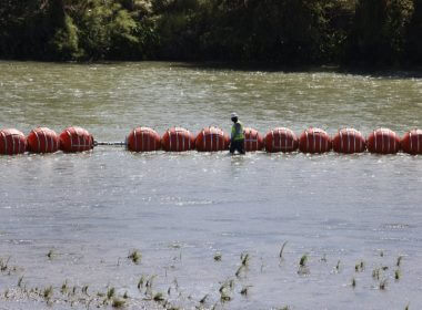 A worker walks by buoys that were placed in the Rio Grande in Eagle Pass, Texas, earlier this month. File Photo by Adam Davis/EPA-EFE