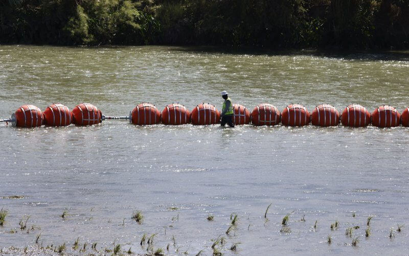 A worker walks by buoys that were placed in the Rio Grande in Eagle Pass, Texas, earlier this month. File Photo by Adam Davis/EPA-EFE