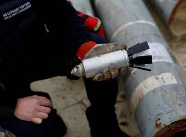 Ukrainian military serviceman Igor Ovcharruck holds a defused cluster bomb from an MSLR missile, among a display of pieces of rockets used by Russian army, that a Ukrainian munitions expert said did not explode on impact, in the region of Kharkiv, Ukraine, October 21, 2022. REUTERS