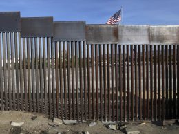 A United States flag flies behind the border fence that divides Mexico and the U.S., in Tijuana, Mexico, Nov. 21, 2018. Nearly a thousand migrants that recently crossed from Guatemala into Mexico formed a group Saturday, July 15, 2023, to head north together in hopes of reaching the border with the United States. (AP Photo/Rodrigo Abd, File)