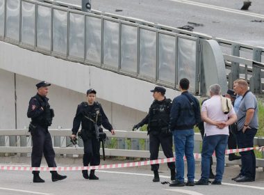 A police officer carries debris to the members of the security services investigating a bridge near the site of a damaged building following a reported drone attack in Moscow, Russia, July 24, 2023. REUTERS