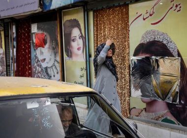 A woman walks past beauty salons with window decorations which have been defaced in Kabul, Afghanistan, Sunday, Sept. 12, 2021. (AP Photo/Bernat Armangue, File)