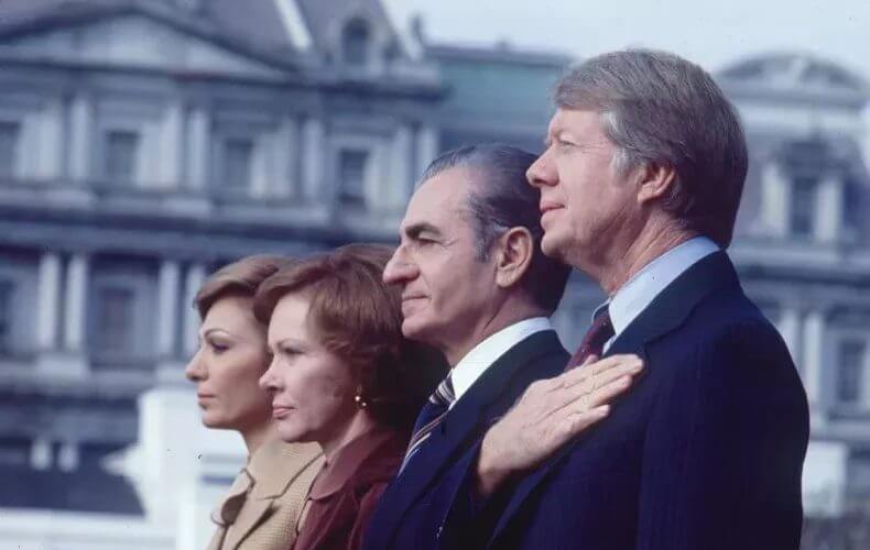 View of, in profile from left, Empress Farah Pahlavi of Iran, First Lady Rosalynn Carter, the Shah of Iran Emperor Reza Palhevi, and President Jimmy Carter as they stand for their respective country's national anthems during a welcoming ceremony at the White House, Nov. 15, 1977. PHOTO BY DIANA WALKER/GETTY IMAGES