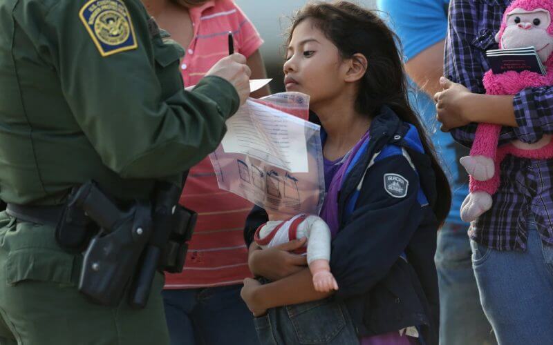 Stefany Marjorie, 8, watches as a U.S. Border Patrol agent records family information on July 24, 2014 in Mission, Texas. (Photo by John Moore/Getty Images)
