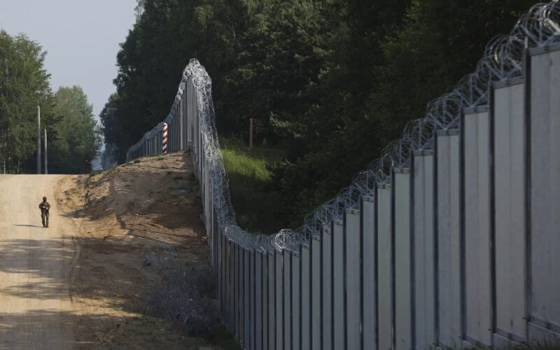 A Polish border guard patrols the area of a built metal wall on the border between Poland and Belarus, near Kuznice, Poland, on June 30, 2022. AP