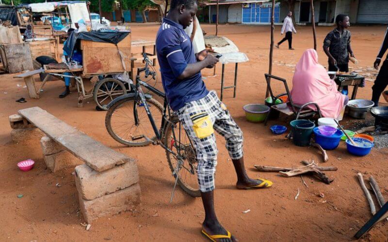 A man checks his phone in Niamey, Niger, Friday, Aug. 11, 2023. (AP Photo/Sam Mednick)