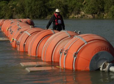 A kayaker walks past large buoys being used as a floating border barrier on the Rio Grande, Aug. 1, 2023, in Eagle Pass, Texas. (AP Photo/Eric Gay, File)