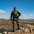 A U.S. Border Patrol agent stands on a cliff looking for migrants that crossed the border wall between the U.S. and Mexico near the city of Sasabe, Arizona, on Jan. 23, 2022. (Salwan Georges/Washington Post via Getty Images)