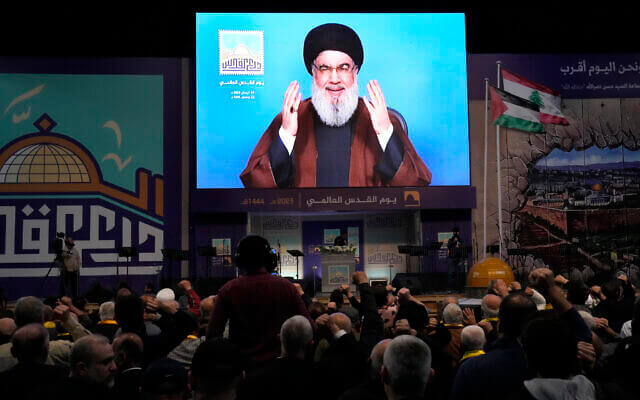 Hezbollah leader Hassan Nasrallah greets his supporters through a screen via a video link from a secret place, during a rally to mark Jerusalem day, in a southern suburb of Beirut, Lebanon, April 14, 2023. (AP Photo/ Hussein Malla)