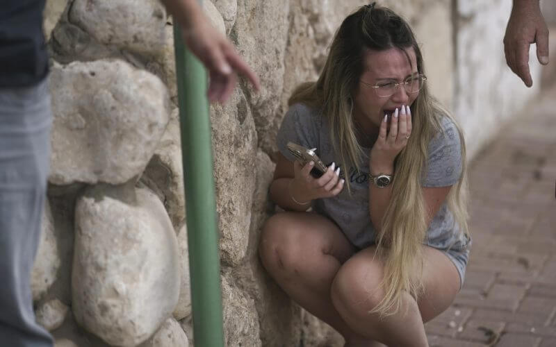 Israelis take cover from incoming rocket fire from the Gaza Strip in Ashkelon, Israel, on Oct. 11, 2023. (AP Photo/Leo Correa)