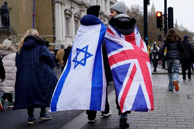 Two protesters wrapped in the flags of Israel and Britain walk in London during a march against anti-Semitism (AP Photo/Alberto Pezzali)