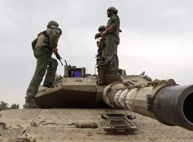 Israeli army soldiers position themselves with their Merkava tanks near the boundary with the Gaza Strip, on 9 October 2023 (AFP)