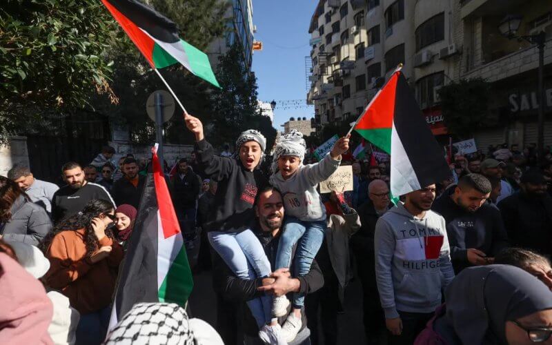 Palestinians wave their national flag and chant slogans during a rally and general strike in Ramallah on December 11, 2023. AFP