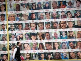 People walk by photographs of Israeli civilians held hostage by Hamas terrorists in Gaza, in Tel Aviv, April 9, 2023. (Miriam Alster/Flash90)