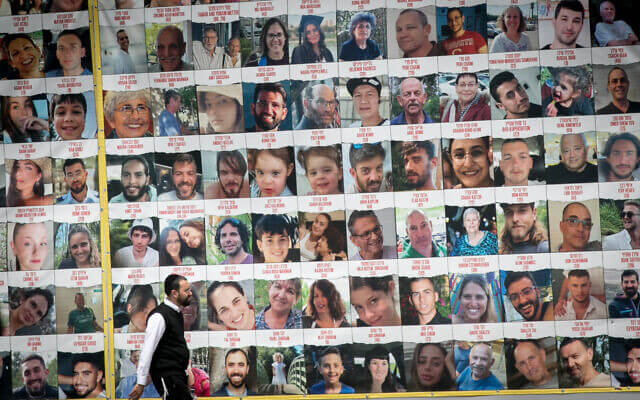 People walk by photographs of Israeli civilians held hostage by Hamas terrorists in Gaza, in Tel Aviv, April 9, 2023. (Miriam Alster/Flash90)