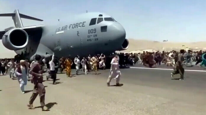People run alongside a U.S. Air Force C-17 transport plane as it moves down a runway of the international airport, in Kabul, Afghanistan, Monday, Aug.16. 2021. AP