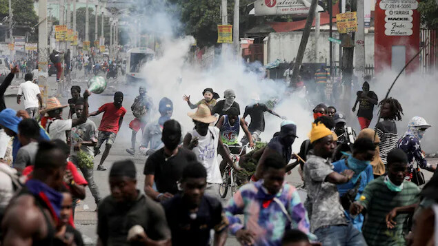 People flee as police fire tear gas during a protest demanding the resignation of Haiti's Prime Minister Ariel Henry in Port-au-Prince on Oct. 10, after weeks of food and fuel shortages. Reuters