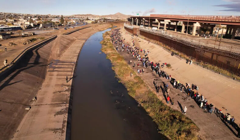 Migrants line up near the border wall after crossing the Rio Bravo River to turn themselves in to U.S. Border Patrol agents to request asylum in El Paso, Texas. Reuters