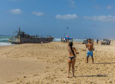 Israelis stand near a US Army vessel that washed up on a beach in Ashdod, May 25, 2024. (Liron Moldovan/Flash90)