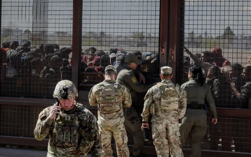Members of the Texas National Guard and Border Patrol agents at a border gate where migrants who forced their way through concertina wire wait to be processed by the Border Patrol in El Paso on March 21, 2024. Reuters