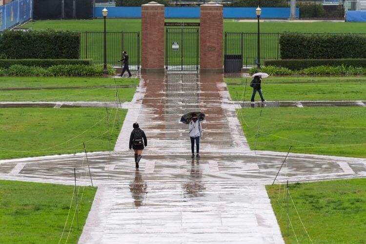 Students walk through Wilson Plaza during a rainy day on campus at the University of California, Los Angeles.