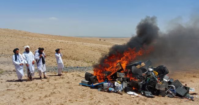 Members of the Taliban morality police stand beside a bonfire of musical instruments and equipment they confiscated and burned in the Western Afghan city of Herat. AFP