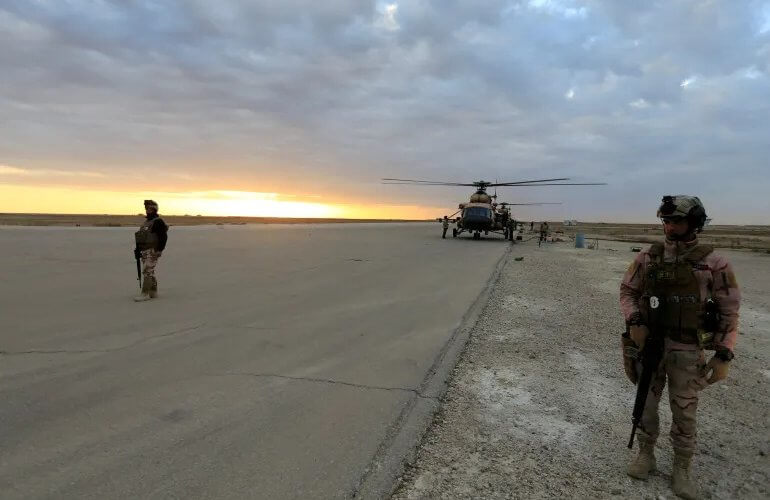 Iraqi security forces are seen at al-Assad airbase near a military helicopter in Anbar province. Reuters