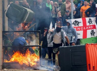 Rioters throw a garbage bin on fire outside a hotel in Rotherham. Reuters