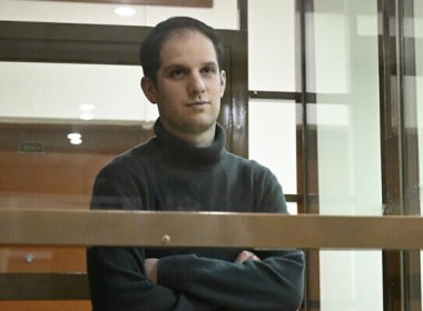 Wall Street Journal reporter Evan Gershkovich stands in a glass cage in a courtroom. AP