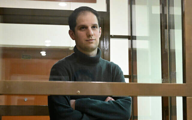 Wall Street Journal reporter Evan Gershkovich stands in a glass cage in a courtroom. AP