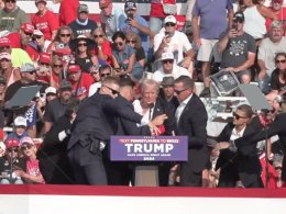 A bloodied former President Donald Trump is lifted from the podium floor after an assassination attempt in Butler, Pa., on Saturday, July 13, 2024. facebook.com