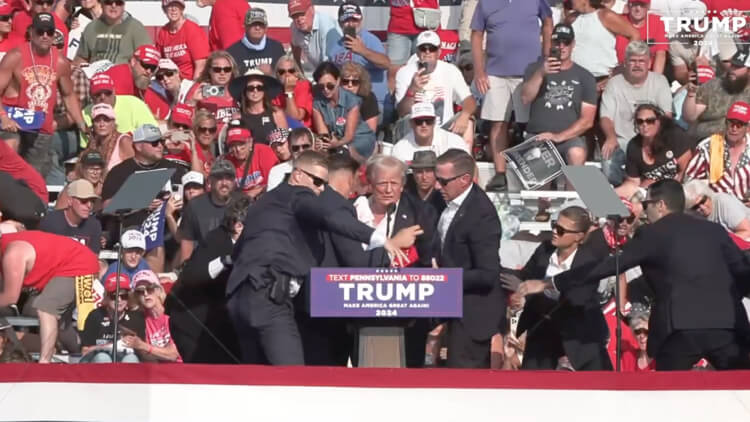 A bloodied former President Donald Trump is lifted from the podium floor after an assassination attempt in Butler, Pa., on Saturday, July 13, 2024. facebook.com