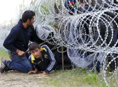 Syrian migrants climb under rolls of razor wire into Hungary at the border with Serbia. Reuters