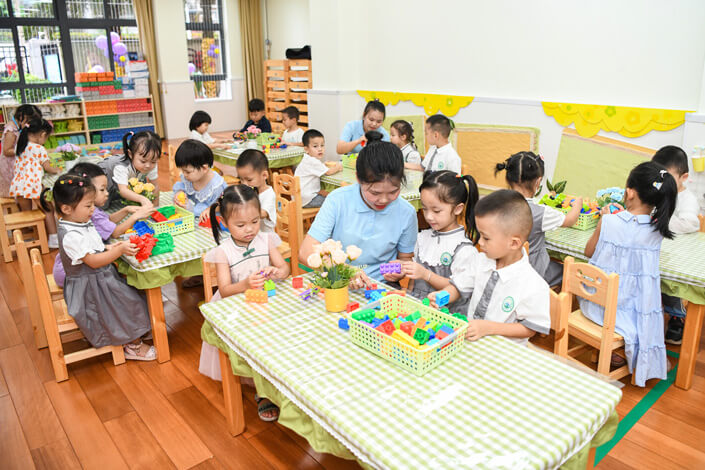 A teacher helps kindergarten pupils in Haikou. VCG